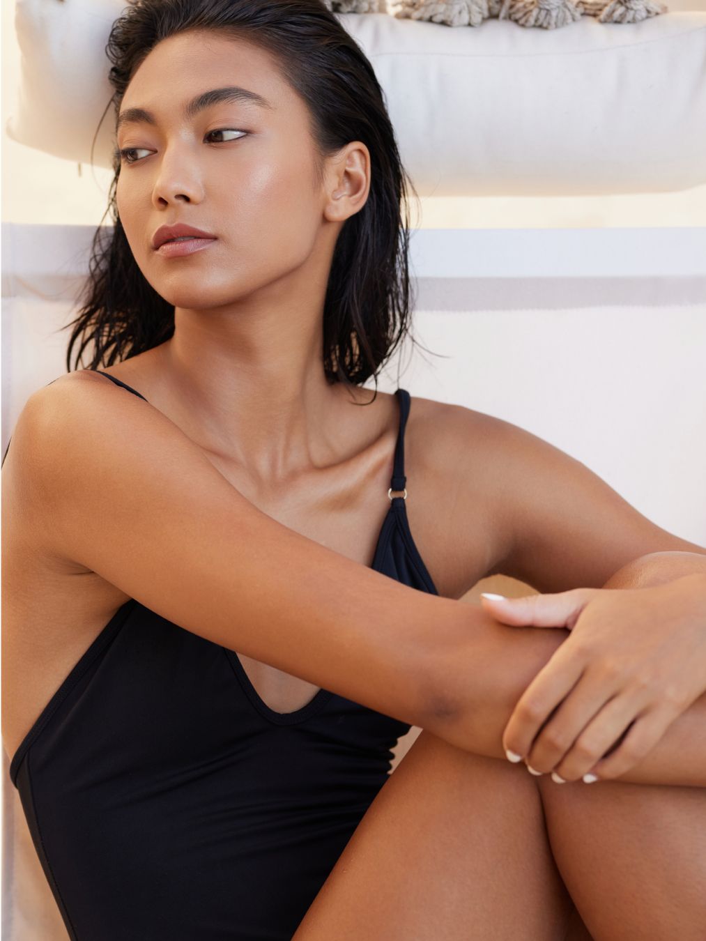 Model in black swimsuit with natural makeup.